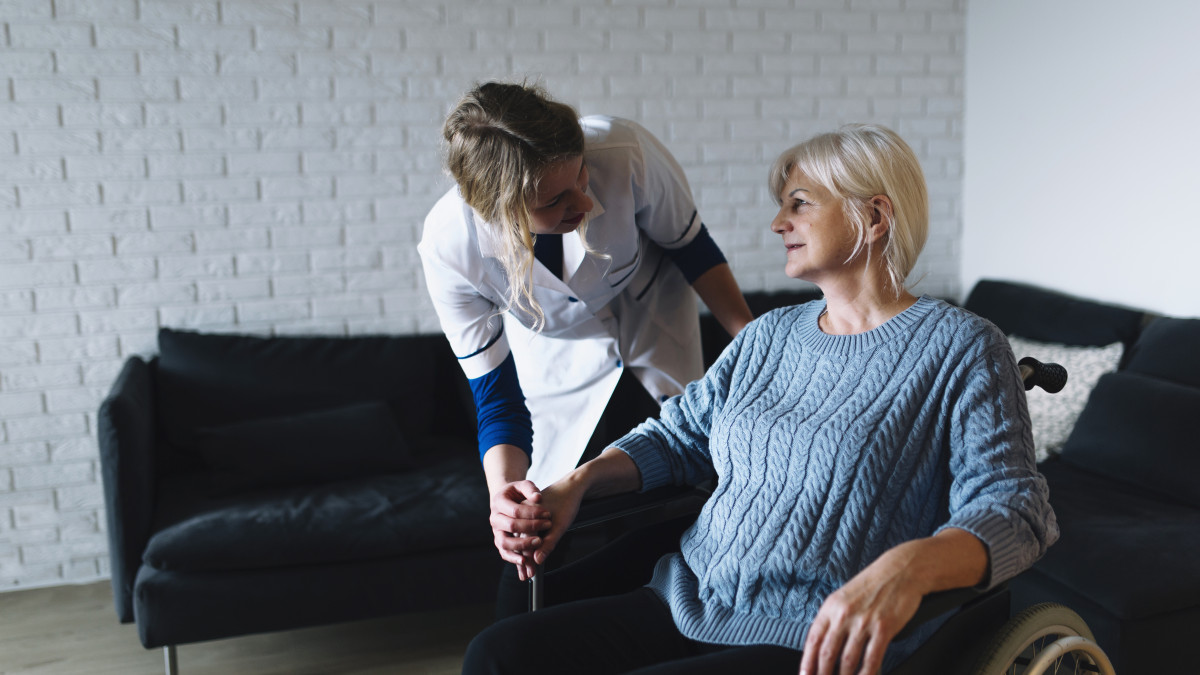 Une jeune aidante s'occupe d'une dame agée à son domicile. 